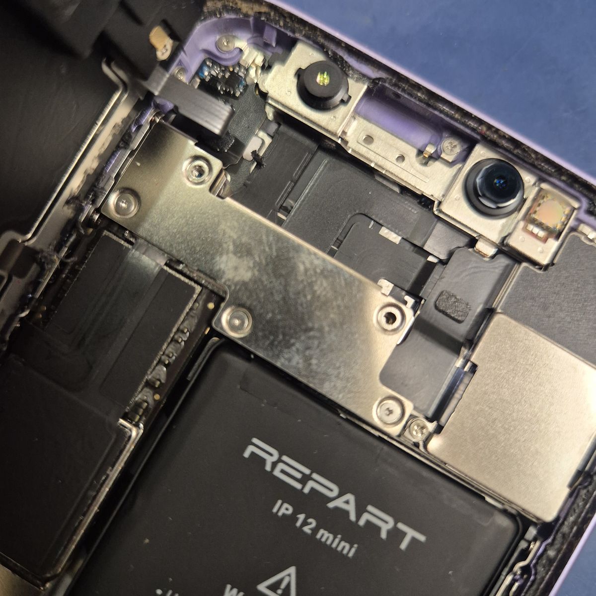 Wnętrze iPhone 12 mini: bateria po wcześniejszej wymianie i osłona złączy bez dwóch śrubek — serwis TELFOX Siemiatycze