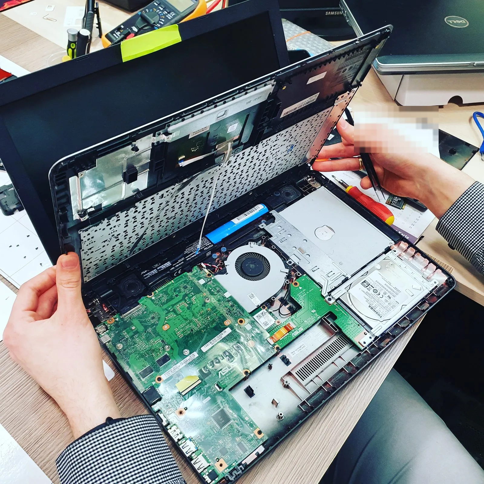 Naprawa laptopa w serwisie TELFOX w Siemiatyczach — otwarty laptop, płyta główna i dysk na stole serwisowym